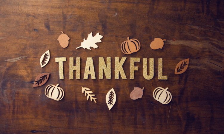 "Thankful" spelled out on a table with pumpkin and leaves art.