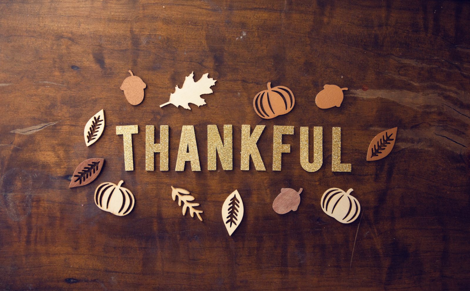 "Thankful" spelled out on a table with pumpkin and leaves art.