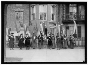 Suffragists holding flags.