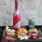 Cheese and meat platter with champagne and champagne glasses.